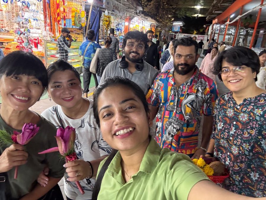 Nap Manor guests on the city tour at a Mumbai temple flower market, holding lotus flowers and an offering basket