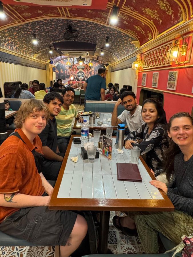 Nap Manor guests and staff sharing a meal on the food tour, at a railway-carriage themed restaurant in Bandra